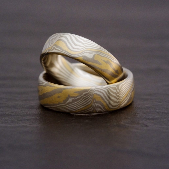 Gemaserte Eheringe aus Palladium, Gold und Silber mit unterschiedlich dicken Linien wodurch die die Maserung organisch und sehr natürlich wirkt.
