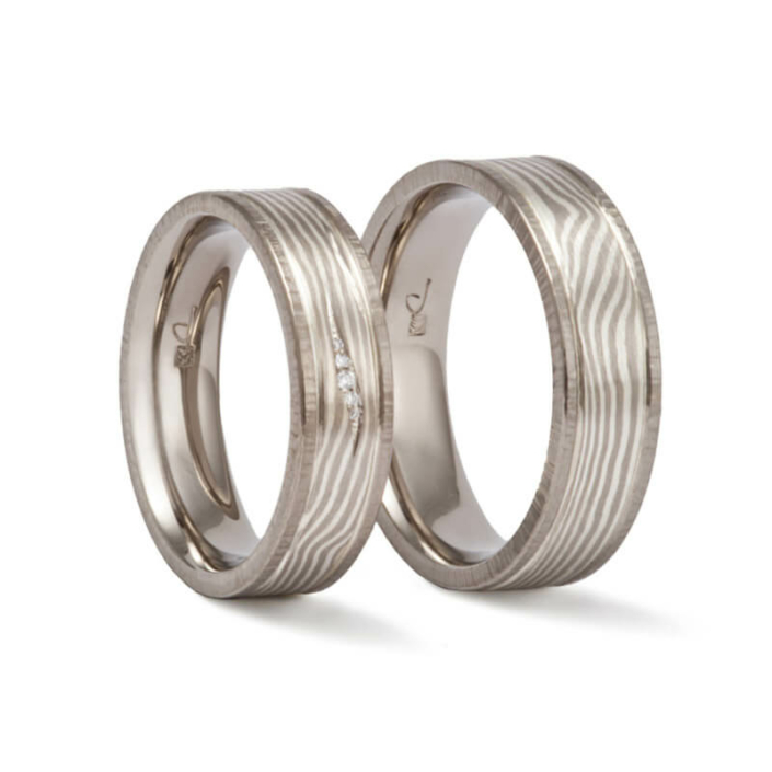 hochzeitsringe_mokume_gane Hochzeitsringe mit fließenden Mokume Gane Linien, gehämmerten Rand aus Palladium und zartem Diamantbesatz im Damenring.