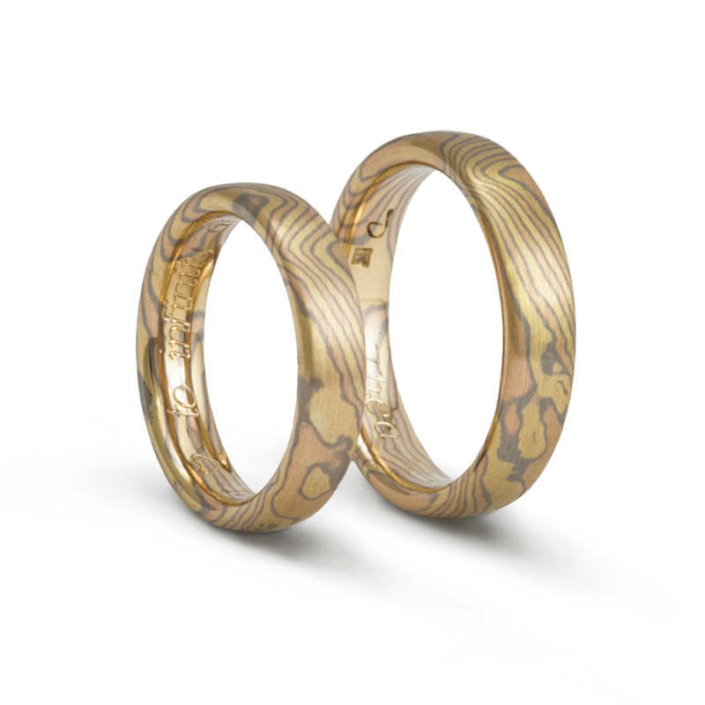 ringe_holzmaserung Dreifarbige Mokume Gane-Partnerringe mit holzähnlichem Muster aus Grau-, Gelb- und Roségold.